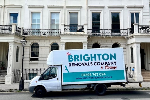A white Brighton Removals Company & Storage van parked in front of a stone terrace building with balconies.