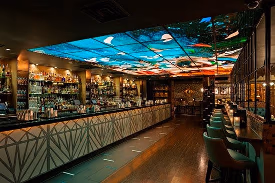The interior of Dirty Martini bar with a long counter, stools, and a ceiling display.
