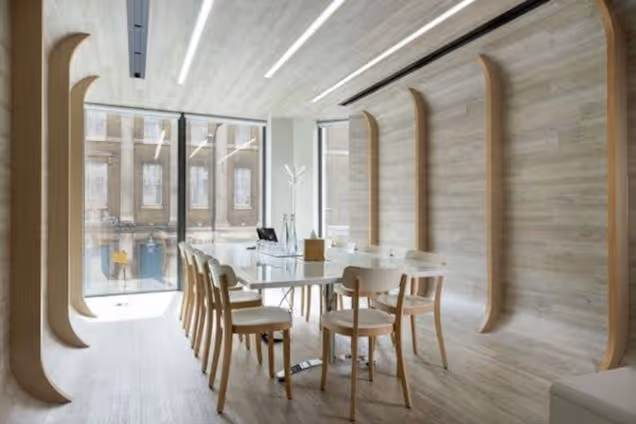 A meeting room with a white table and chairs in a space featuring wood panelling on the floor, walls, and ceiling.