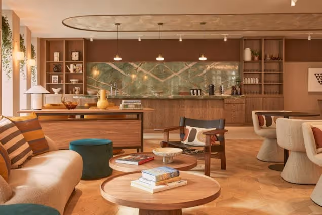 Low tables and sofas in a lounge with a wooden bar and shelves in the background.