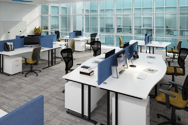 Rows of white desks with blue privacy screens and chairs on a grey carpeted office floor.