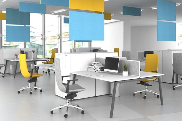 Yellow and grey chairs at white desks in an office with blue and yellow panels hanging from the ceiling.