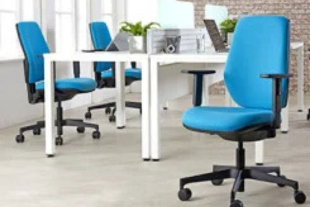 Blue posture chairs at white desks in an office furniture showroom.