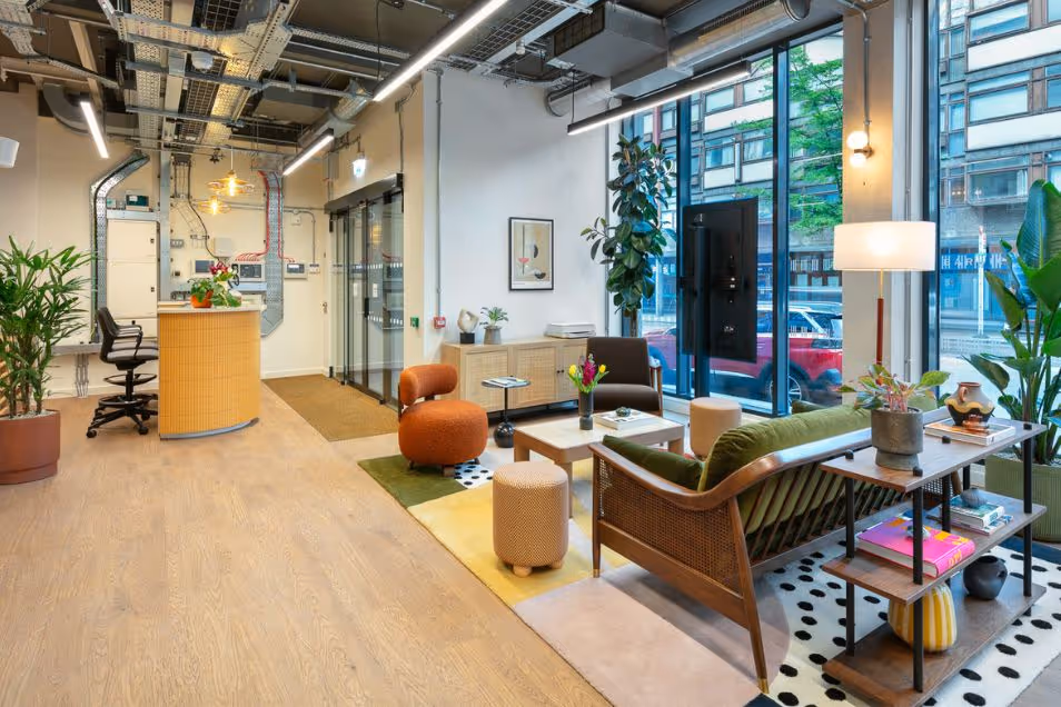 An office reception and lounge featuring a curved wooden desk, mid-century modern furniture, and floor-to-ceiling windows.