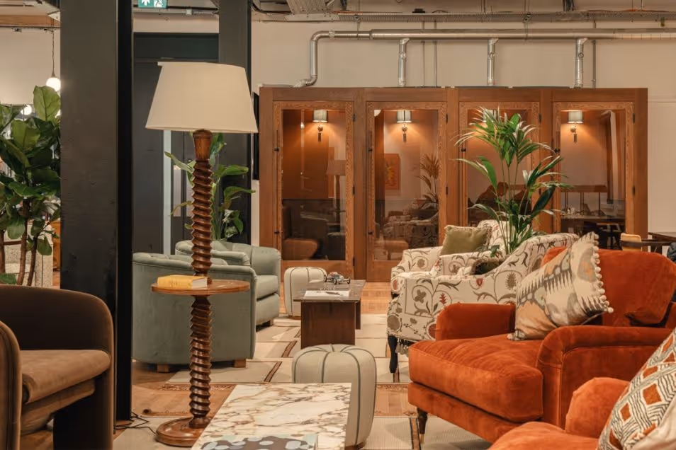 A lounge area with several armchairs and a floor lamp sits in front of wooden phone booths.