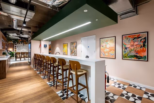 Stools at a white tall counter in a room with paintings on the wall and a checkered floor.