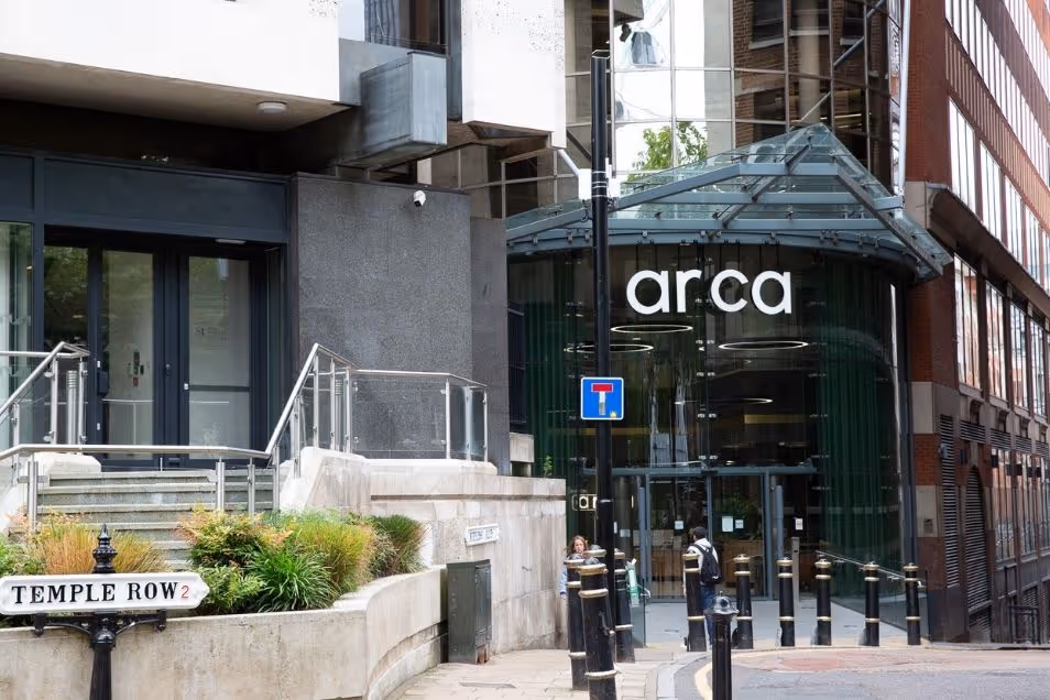 Entrance to the "arca" building, featuring a curved glass storefront and a "TEMPLE ROW" street sign in the foreground.