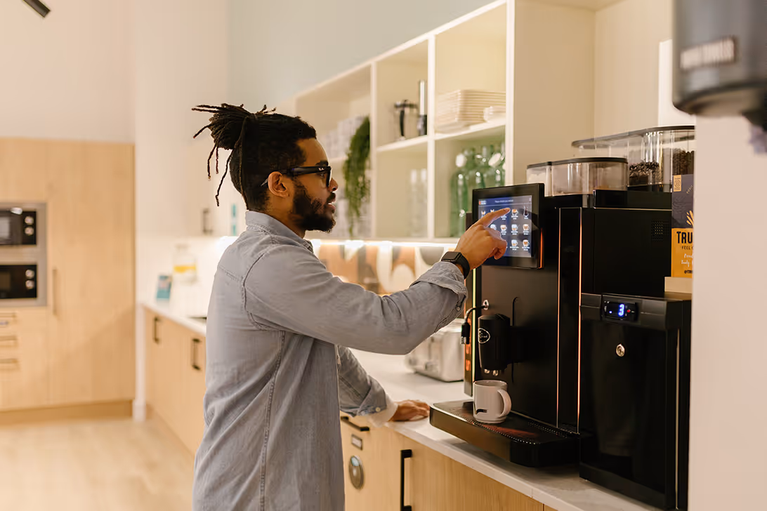 Man filling up his coffee cup at a coffee machine