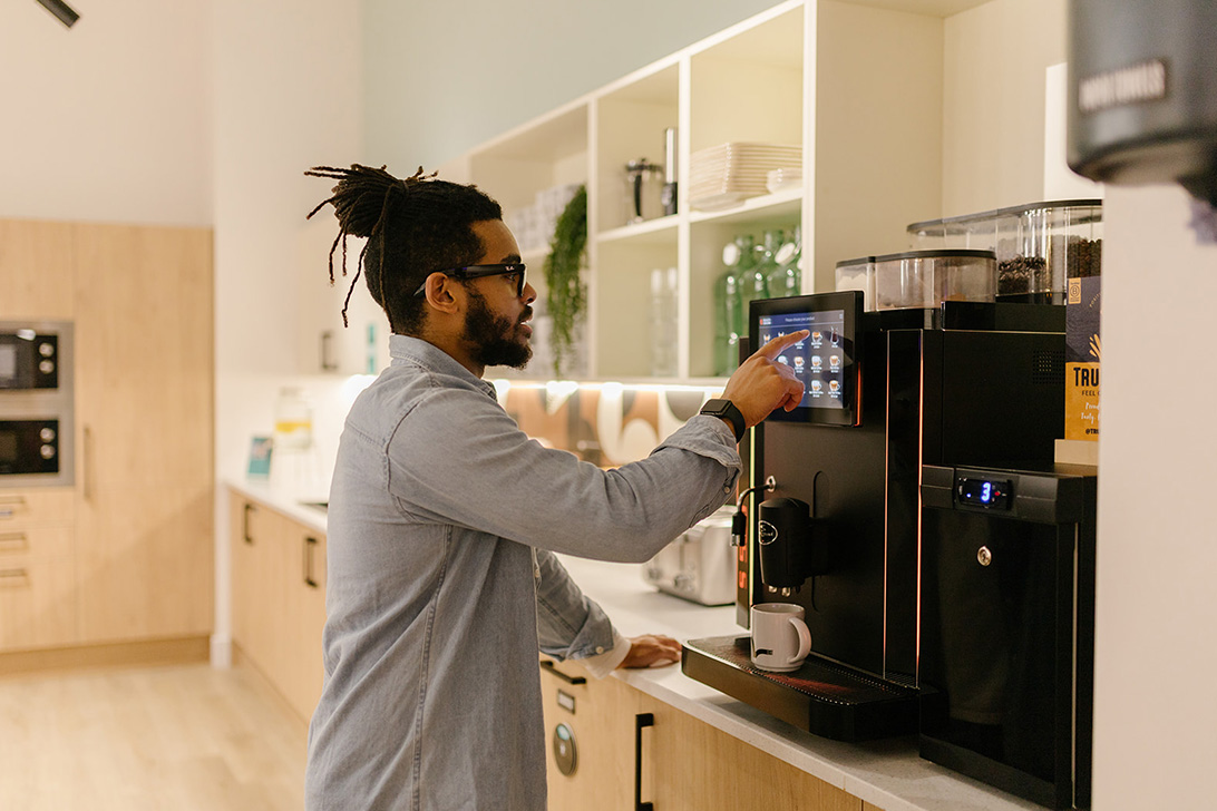 Man filling up his coffee cup at a coffee machine