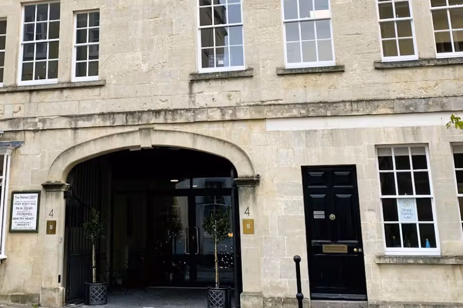 Historic stone building facade featuring a large arched entryway, white-framed sash windows, and a black front door with gold hardware.