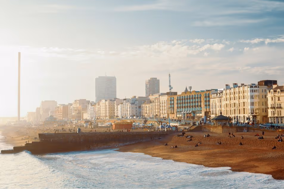 View of Brighton Beach with people sitting on the sand by the sea
