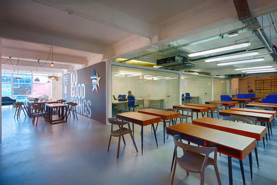 A glass-walled coworking space. Its a large classroom filled with rows of wooden desks.