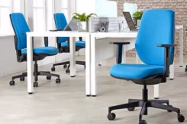 Blue posture chairs at white desks in an office furniture showroom.