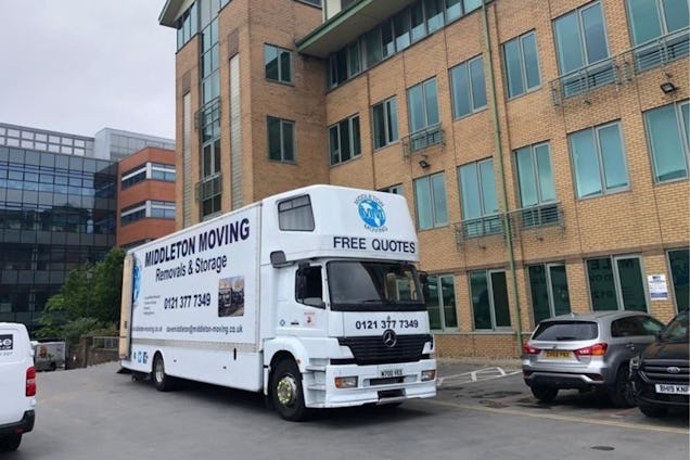 A white Middleton Moving Birmingham removals and storage truck parked in a lot next to a modern office building.