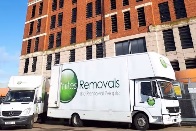 A white Removals truck and a smaller van parked in front of a brick building.