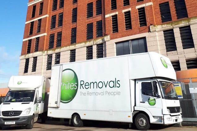 A white Removals truck and a smaller van parked in front of a brick building.