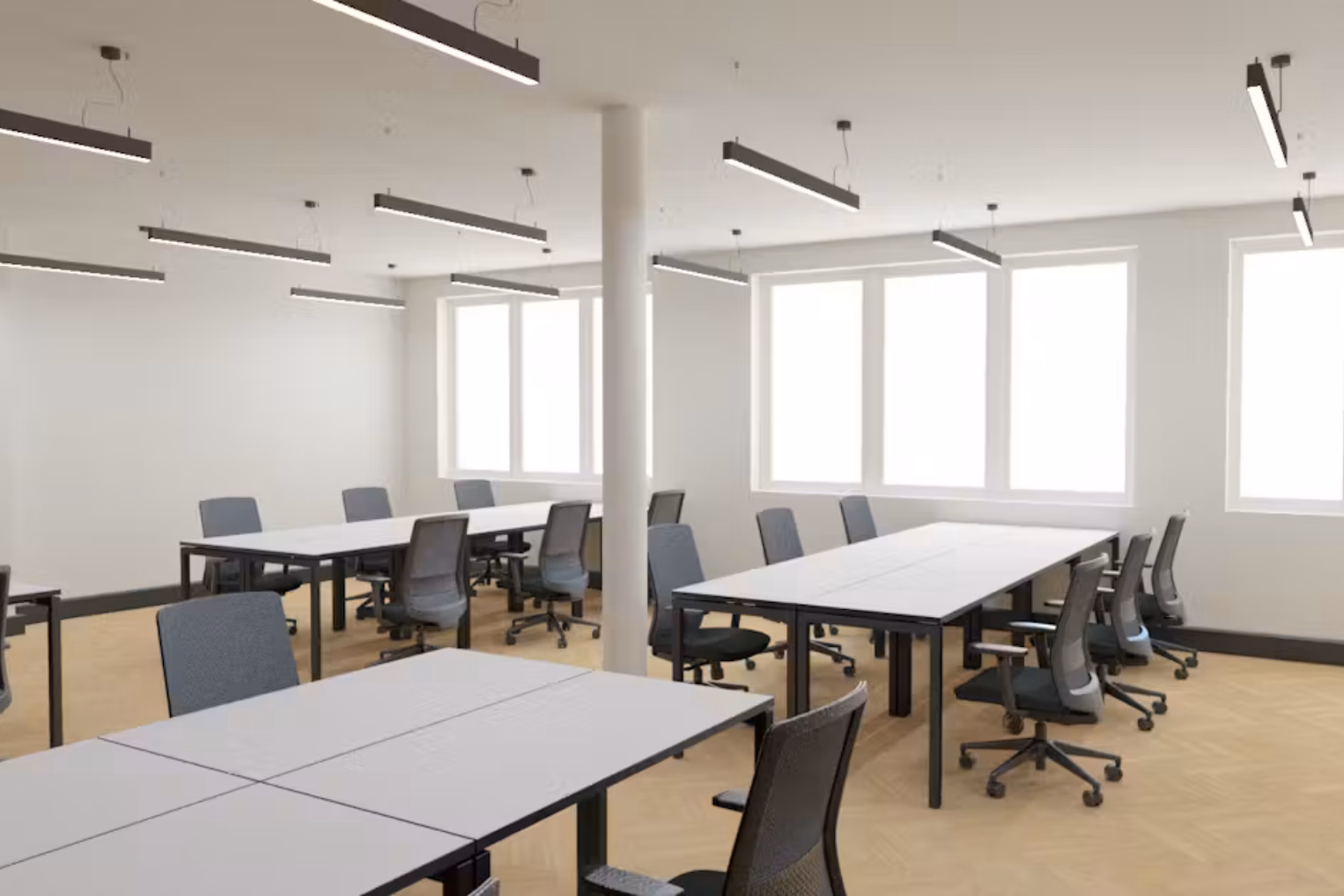 Black chairs at white desks on a wood floor near windows and a pillar under black lights.