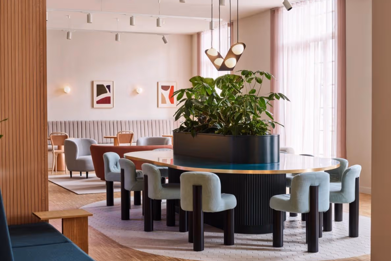 A large teal and black table with light blue chairs sits near grey armchairs and a red sofa.