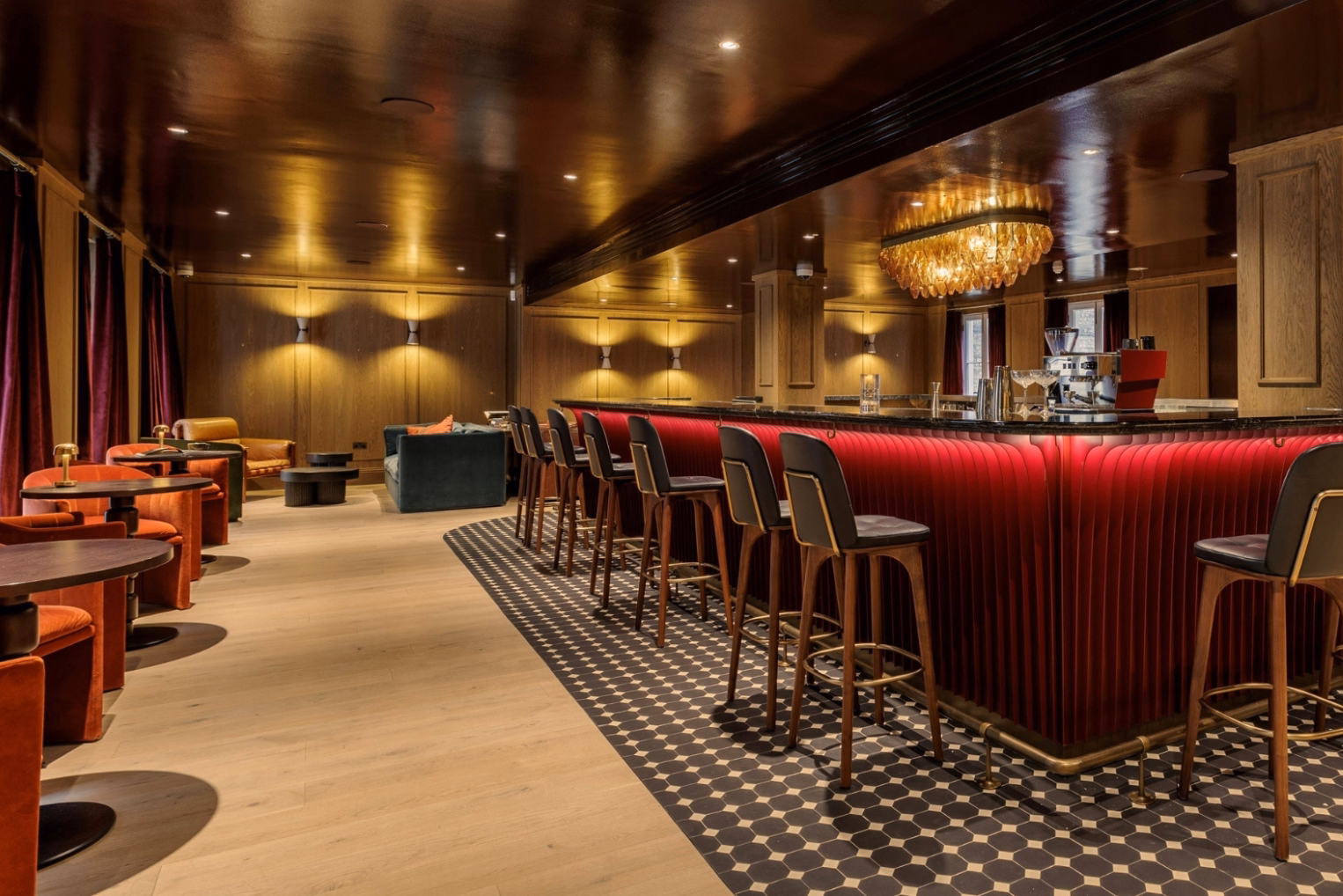Black tools with gold accents line a red bar counter on a black-and-white patterned tile floor.