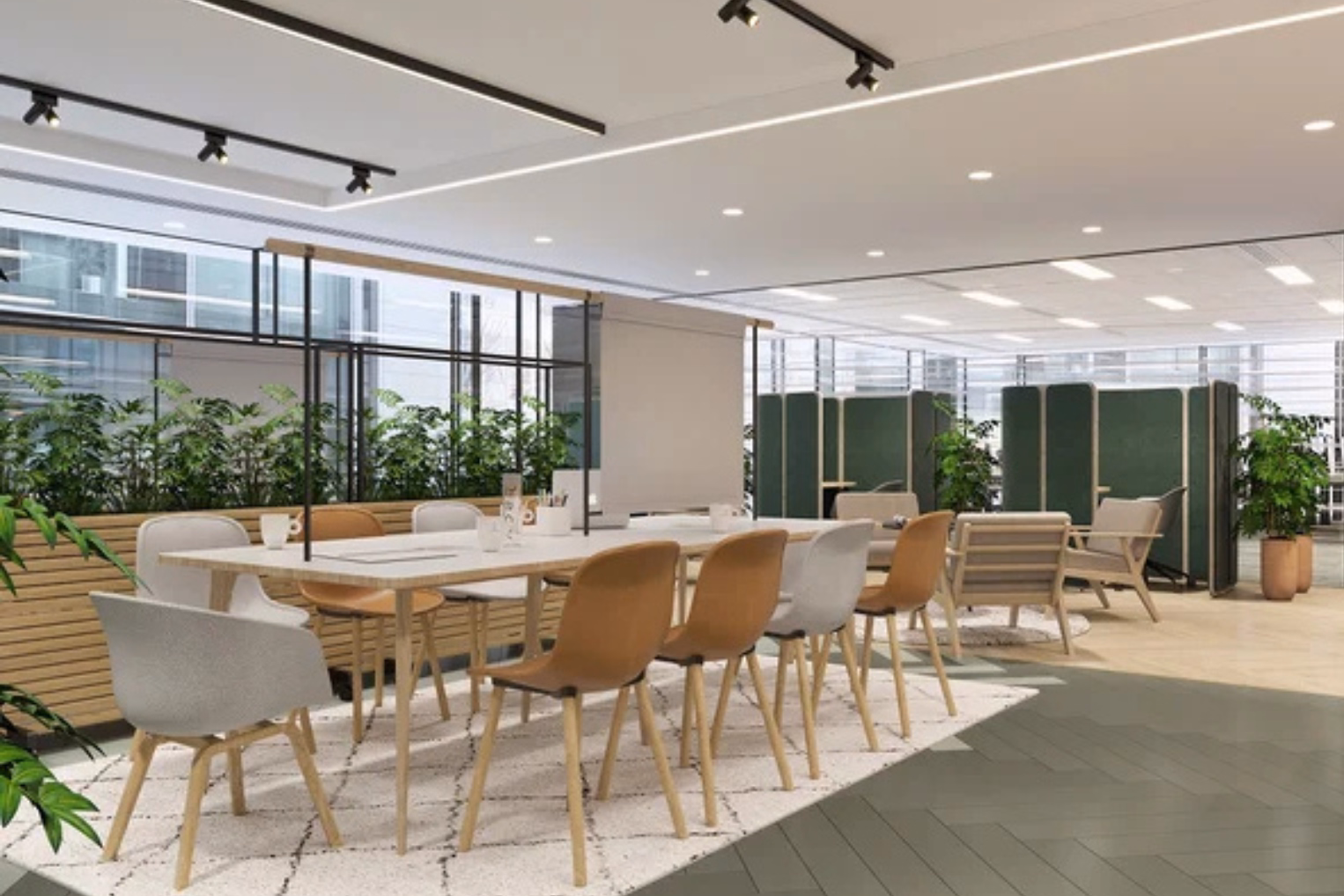 A white table is surrounded by tan and grey chairs on a patterned white rug, with green privacy booths and potted plants dividing the open-plan office lounge.