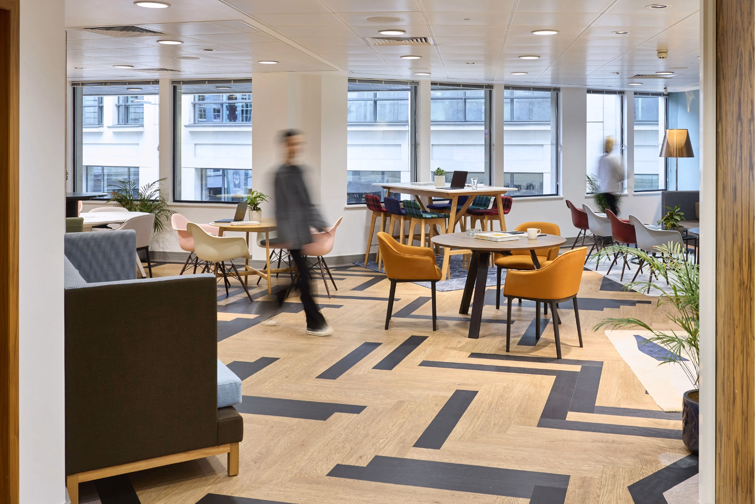 Yellow armchairs surrounding a round table in an office lounge with high-back armchairs and wide windows.