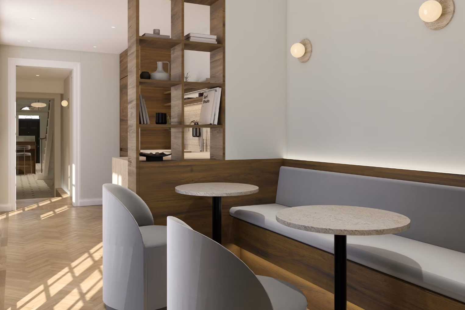 A light grey built-in bench sofa and curved armchairs around marble tables in an office seating nook, featuring open shelving.