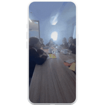 Kids sitting around a table in a meeting room, engaged in conversation.