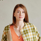Woman in yellow and white plaid button up shirt standing beside kitchen counter