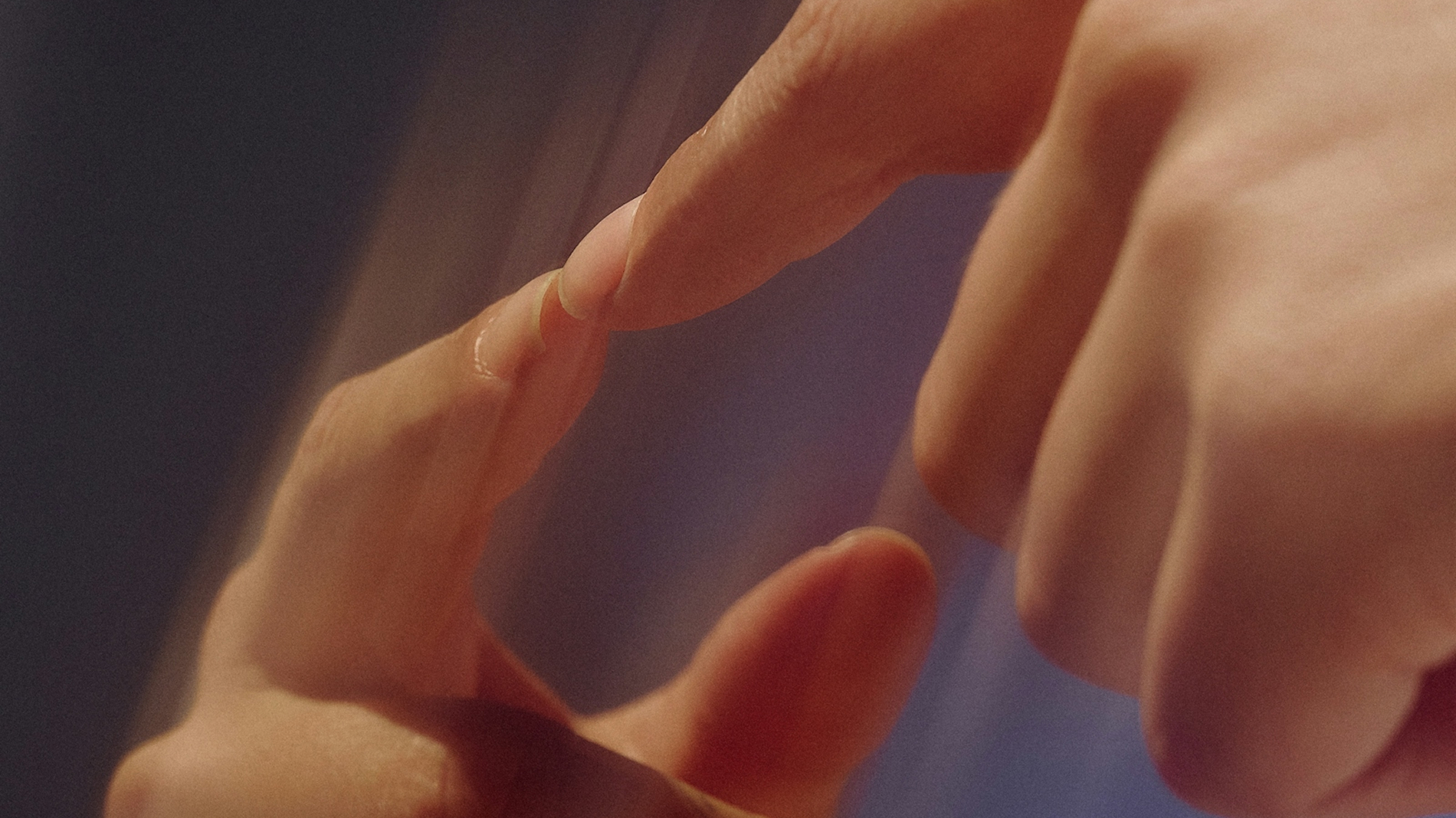 Close-up of two human hands softly touching fingertips in warm lighting.