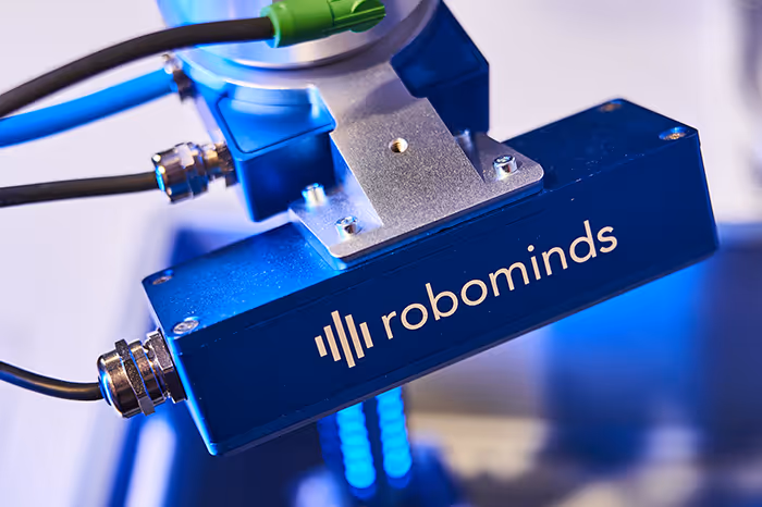 Close-up of a blue robotic device part labeled with the robominds logo and connected cables.