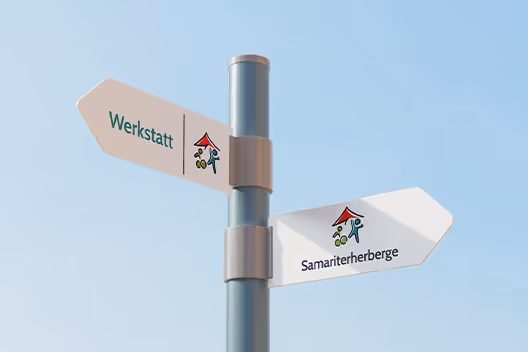 Signpost with two directional arrows labeled 'Werkstatt' and 'Samariterherberge' against a clear blue sky.
