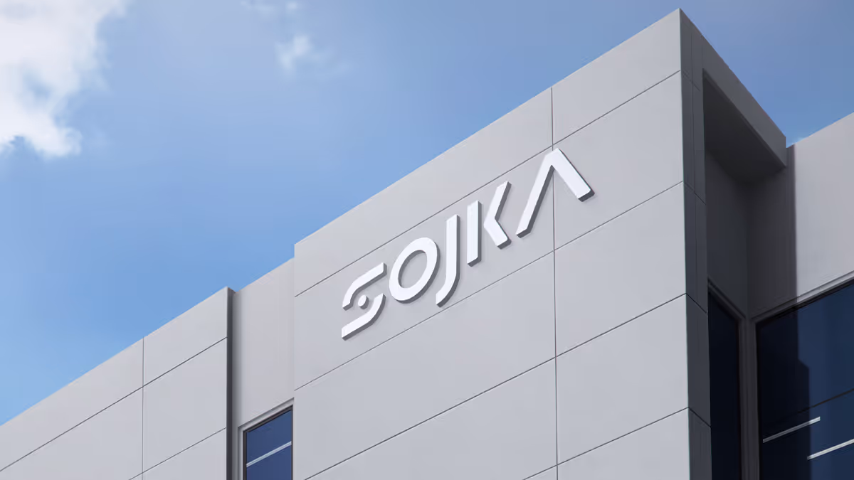 Modern gray building facade with a white SOJKA sign under a blue sky.