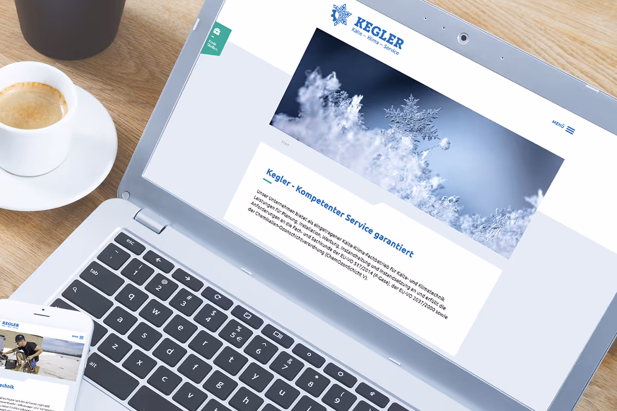 Laptop displaying the Kegler website with a large snowflake and ice crystals image, alongside a cup of coffee and a smartphone showing the same website.