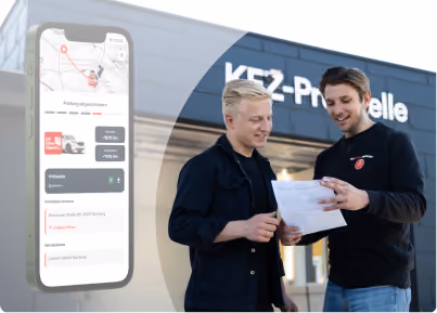Zwei Mitarbeiter besprechen ein Dokument vor einer Kfz-Prüfstelle, daneben ein Smartphone mit Kartenansicht und Buchungsdetails der FleetHub-App.