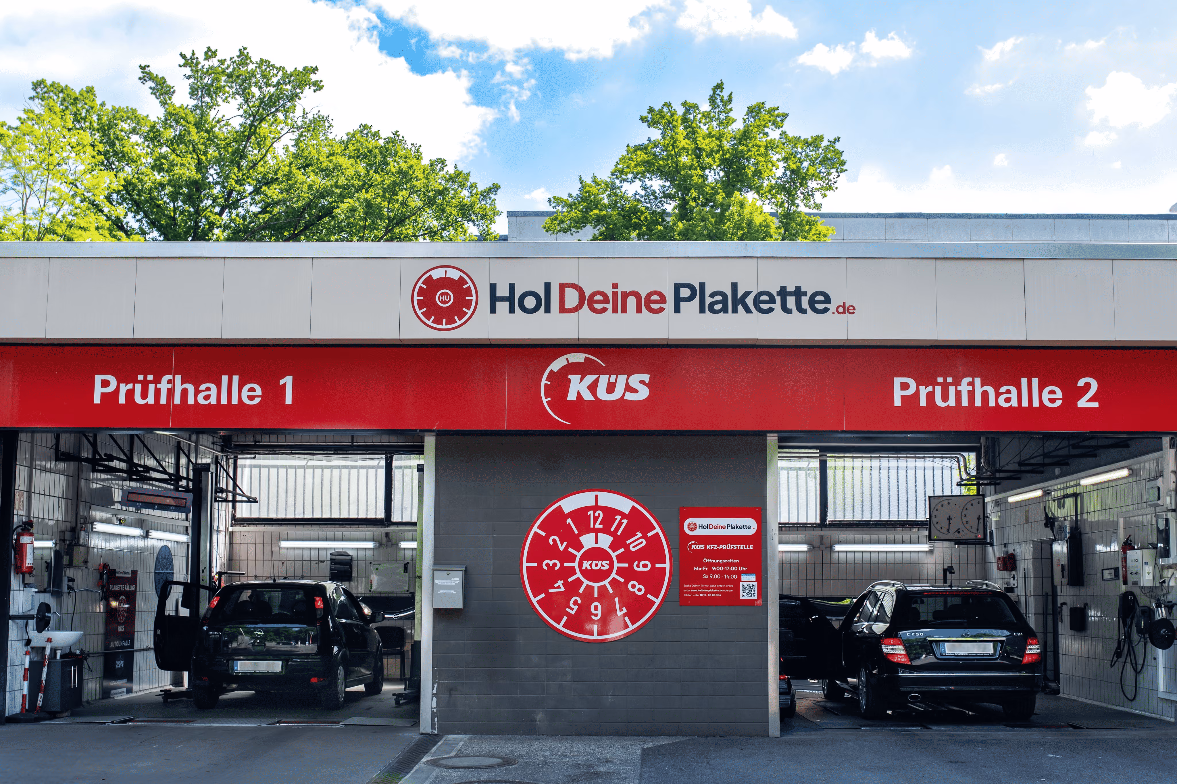 Außenansicht von Prüfhalle 1 und 2 des HolDeinePlakette-Standorts in Nürnberg mit KÜS-Logo.
