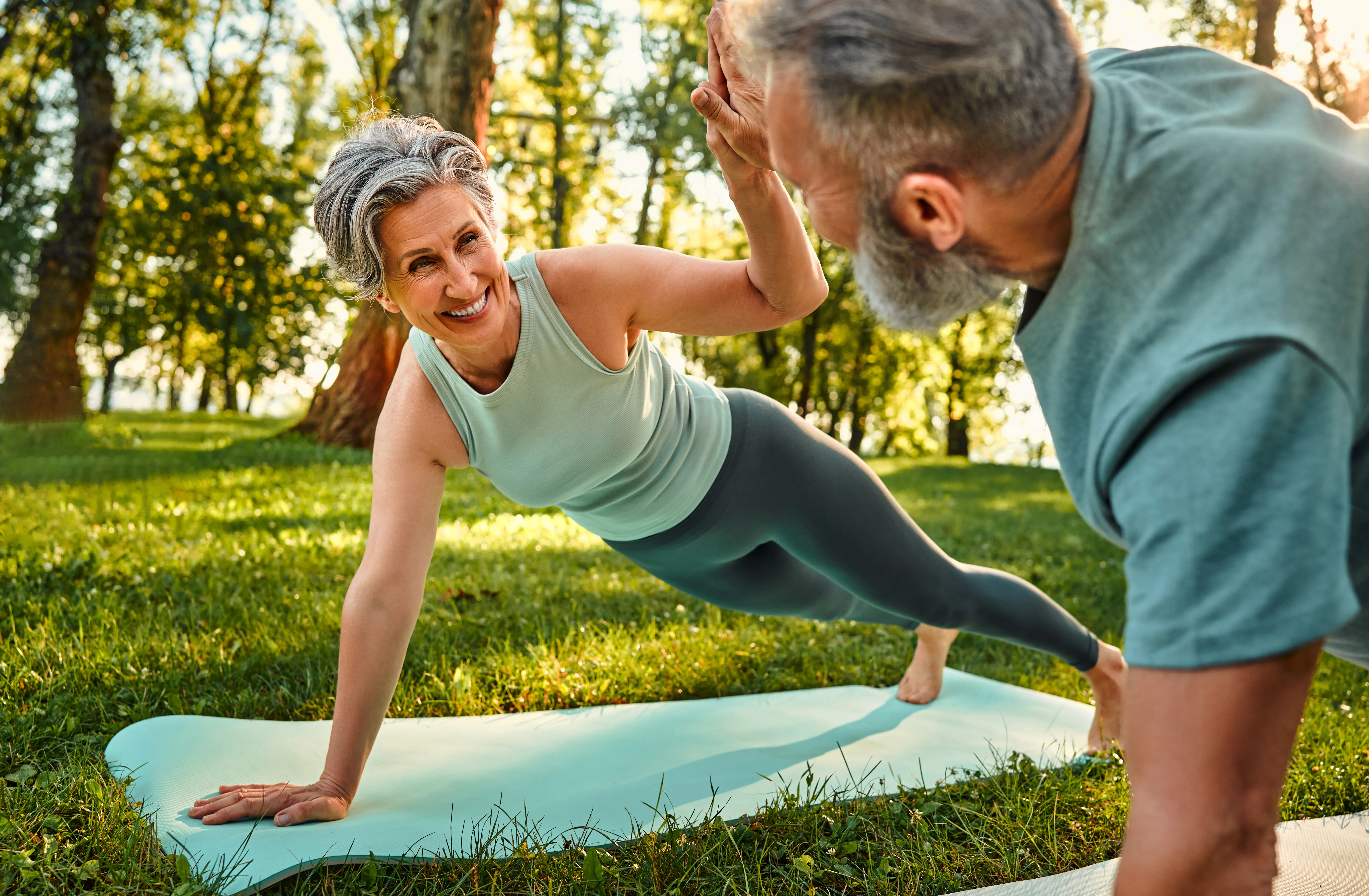 A man and a woman doing yoga in the park.