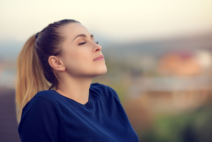 Woman taking deep inhale, blurred town in background