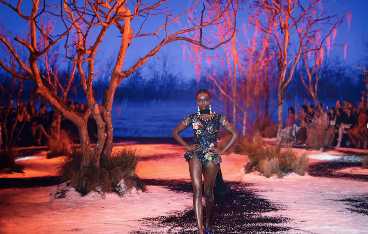 a woman in a dress walking on a path with trees and bushes