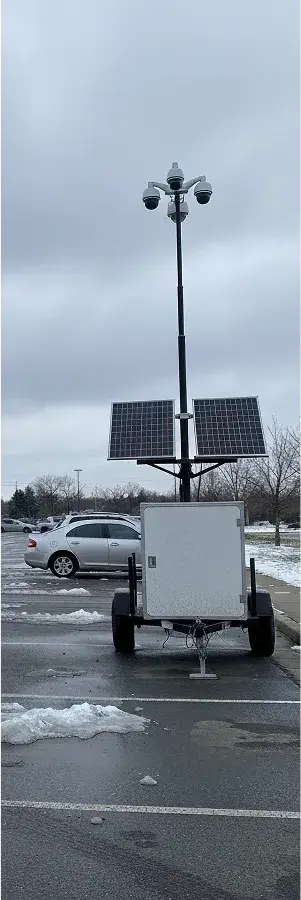Remorque de surveillance mobile avec panneaux solaires déployée dans un parking enneigé.