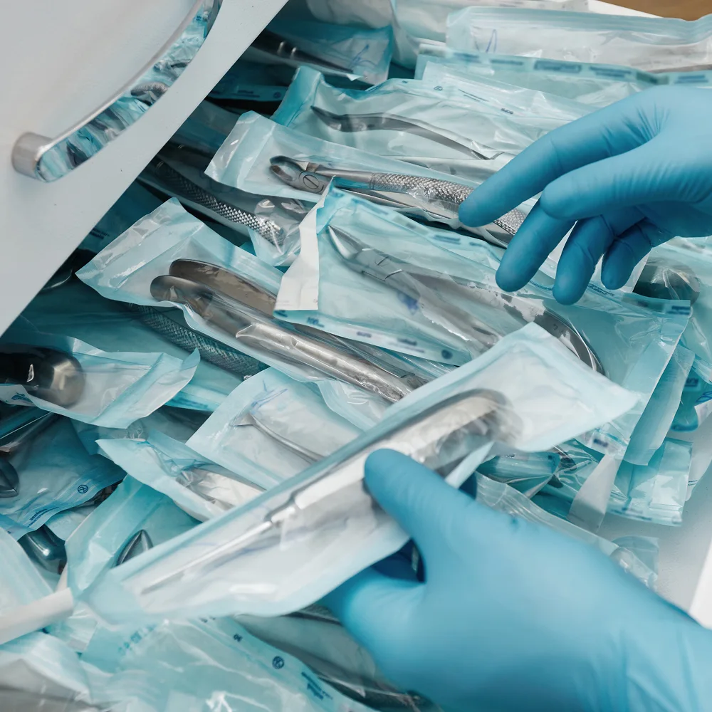 Gloved hands organize sterilized surgical instruments in sealed packaging, emphasizing hospital sterility and surgical tool preparation.