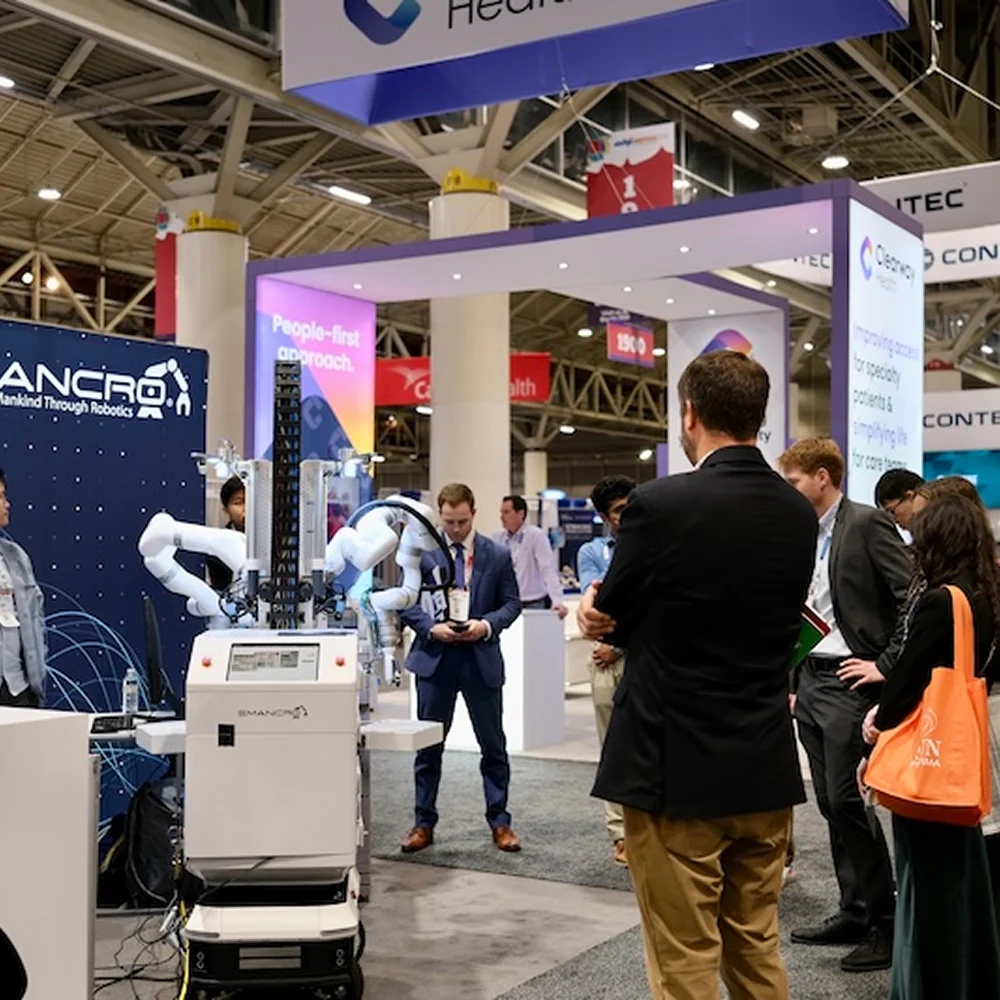 Emancro medical robot demonstrated at an exhibition while a group of visitors observes its operation.