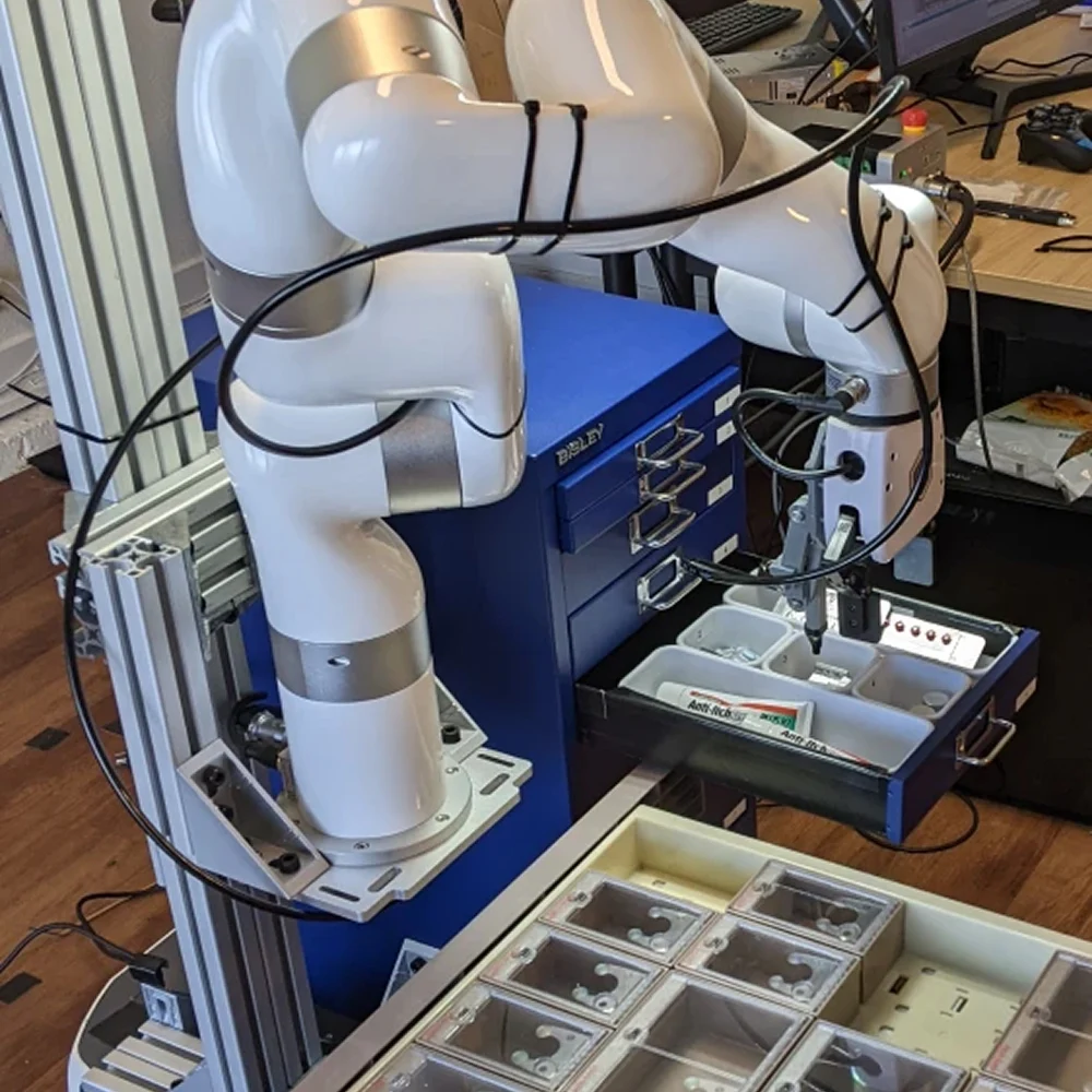 Robotic arm sorting and picking medication containers inside a storage drawer.