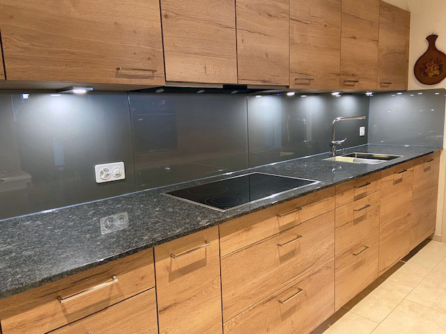 Modern kitchen with wooden cabinets, dark granite countertop, electric stovetop, and stainless steel sink.