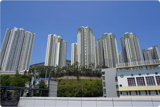 Hong Kong residential towers rising above green hillside under clear blue sky, showing the high-density housing developments where UNC provides community services
