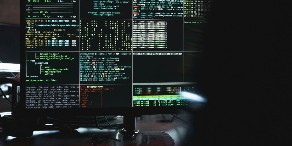 Computer screen with different pieces of programming code on it in dark room