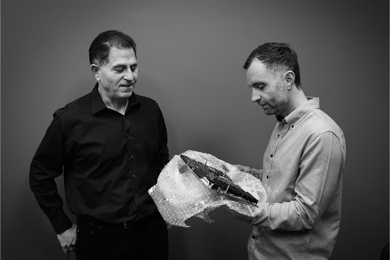 Two men are holding a package together, appearing engaged in conversation about its contents.