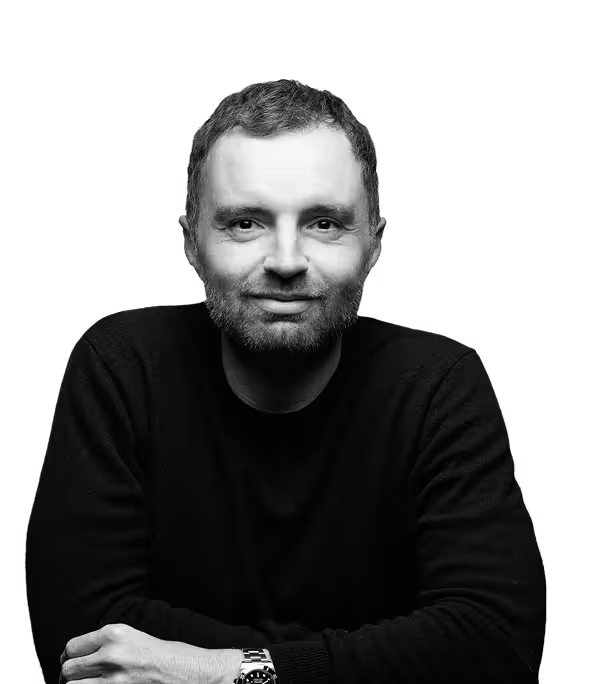 Black and white portrait of a David Senra, wearing a dark sweater and watch, smiling slightly with arms crossed.