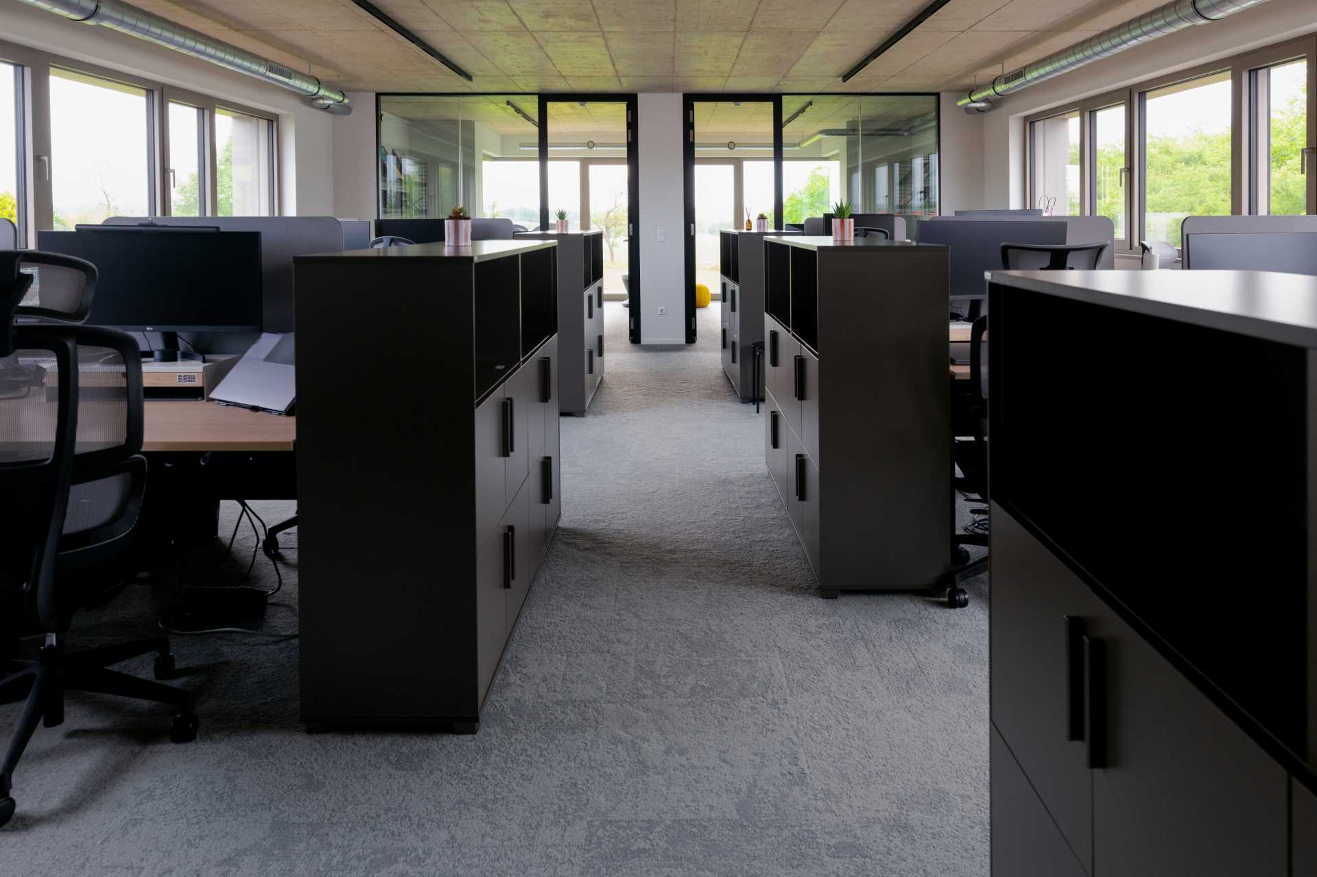 Deux personnes discutant autour d'une table avec des ordinateurs portables ouverts dans un bureau moderne.