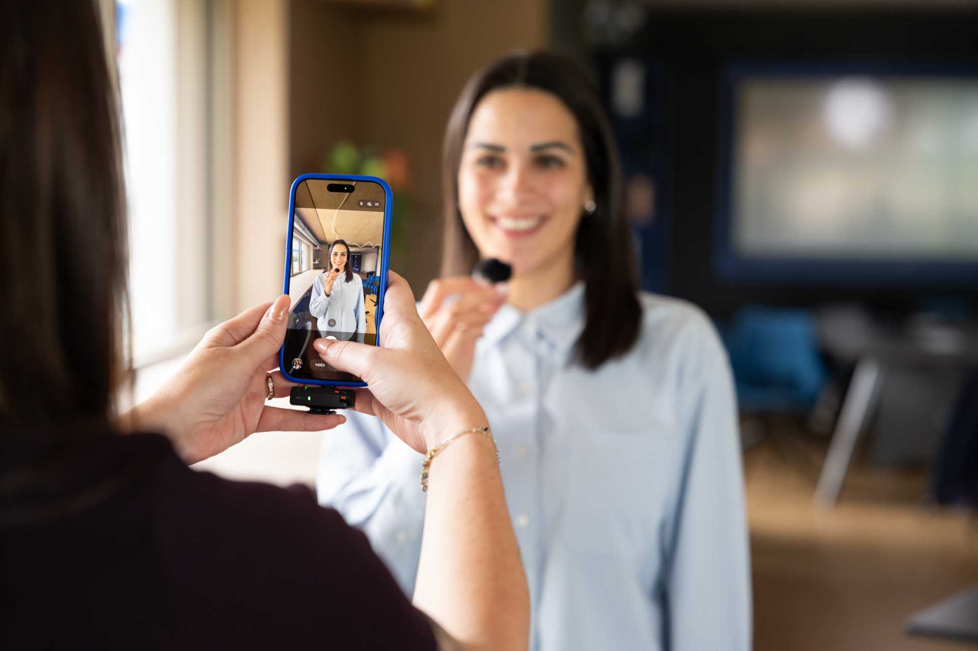 Silhouette d'une personne tenant un smartphone pour filmer un concert avec lumière bleue et rouge en arrière-plan.