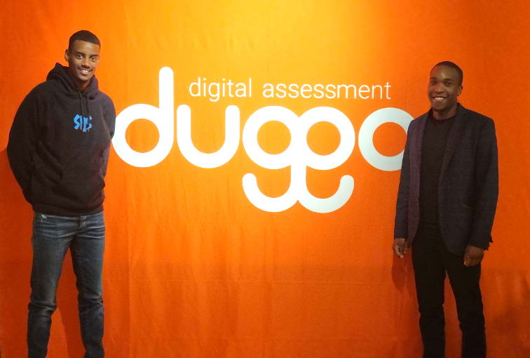 Two smiling men stand before an orange wall with "digital assessment duggo" in white text.